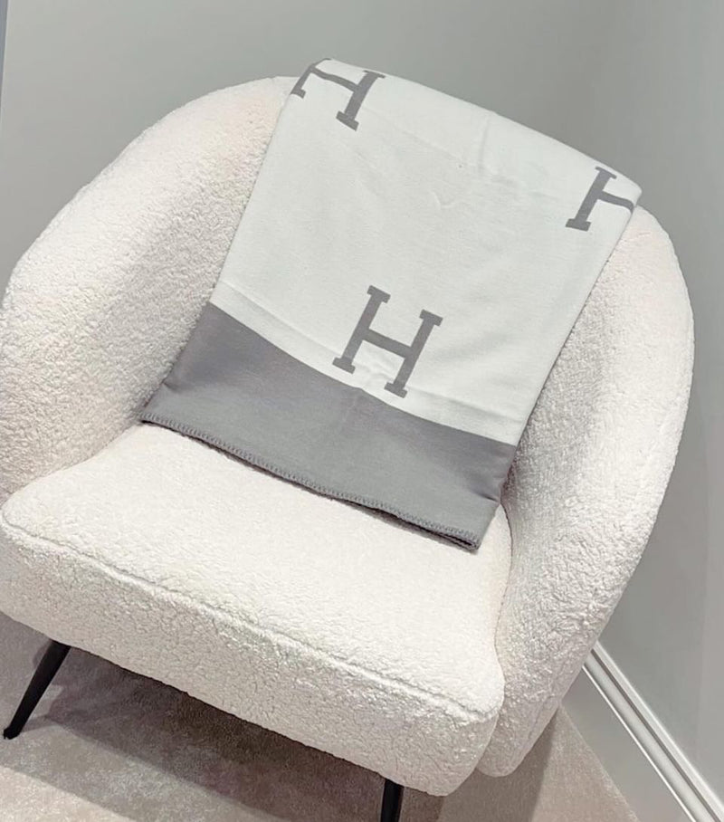 A white chair with a cozy grey and white blanket draped over it. Perfect for the Throwand pyjamas gift bundle worth over £80!