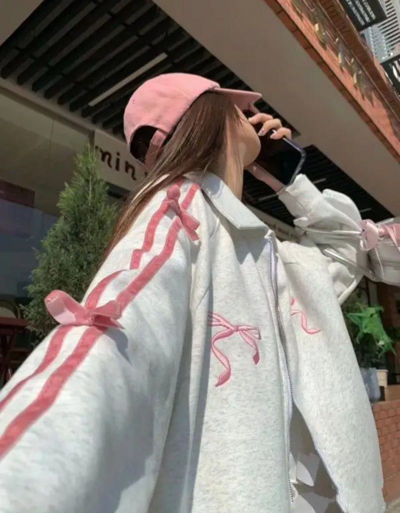 A woman wearing a pink hat and white jacket, showcasing the Grey pink jacket bow zipper ribbon zip up