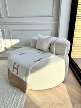 A white couch with a pillow on it. Product name: Throw and Pyjamas gift bundle worth over £80