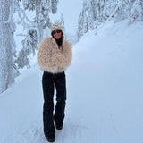 Stylish woman in faux sheep jacket and sunglasses in snowy setting.