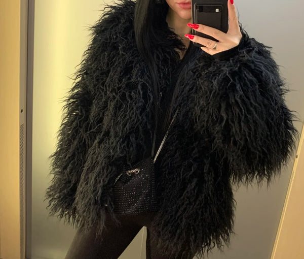 A woman wearing a Black Faux Fur Jacket takes a selfie in a mirror.