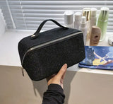 A person holding a black glitter bag - Large sparkle glitter make up toiletry cosmetic bag with handle.