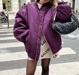 A woman in a purple jacket and black tights confidently crosses the street.