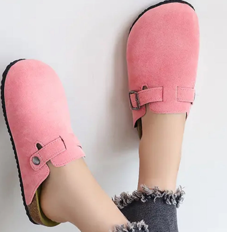 Woman wearing Pink Mules Clogs, pink suede slippers with buckles, providing comfort and style.