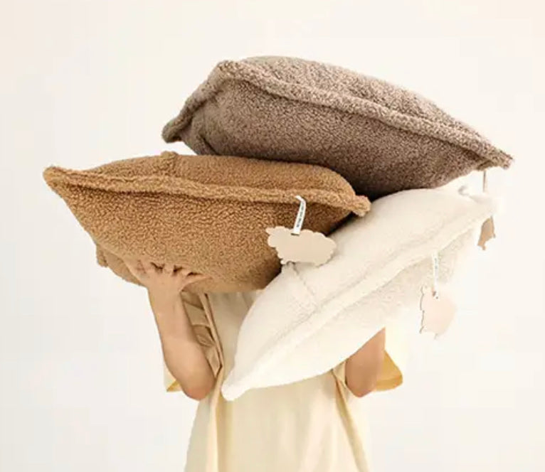 A woman showcasing three plush pillows against a white backdrop - Plush cushion Cover 30x50 boucle