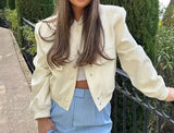 Woman wearing a white jacket and blue skirt, showcasing the Pocket bomber jacket.