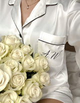A woman in a white robe holds a bouquet of white roses. Product: Throwand pyjamas gift bundle worth over £80!