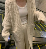 A woman wearing a white cardigan and white pants, showcasing the Knitted long cardigan.