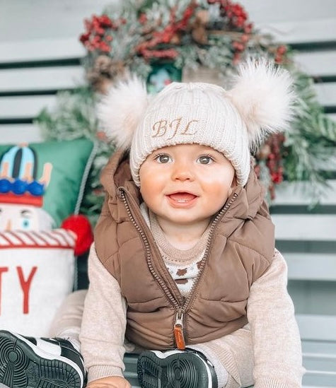 A cute baby wearing a hat and vest, sitting on a bench. Perfect for your little one - Baby And Kids Beanie with fur Embroidered.