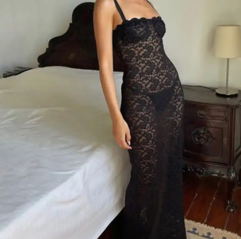 Elegant Black Lace Dress: A woman in a stylish black mesh dress standing in front of a bed.