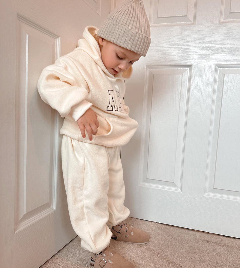 A young child in white hoodie and pants, wearing ABC Kids Soft Tracksuit