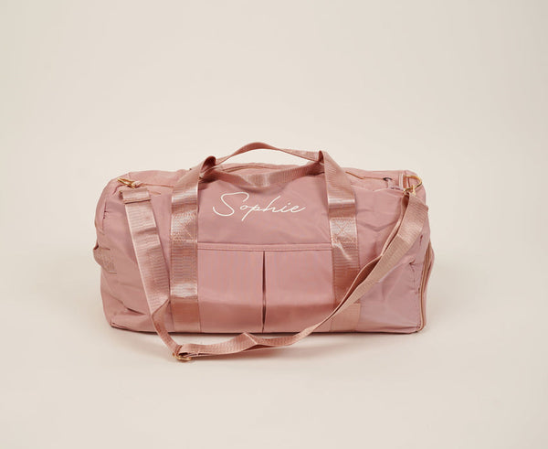 A personalized pink duffel bag with the word "simply" on it, perfect for a weekend getaway.