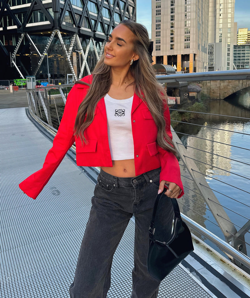 Crop Red Button Jacket: Stylish woman in red jacket and jeans posing on a bridge.